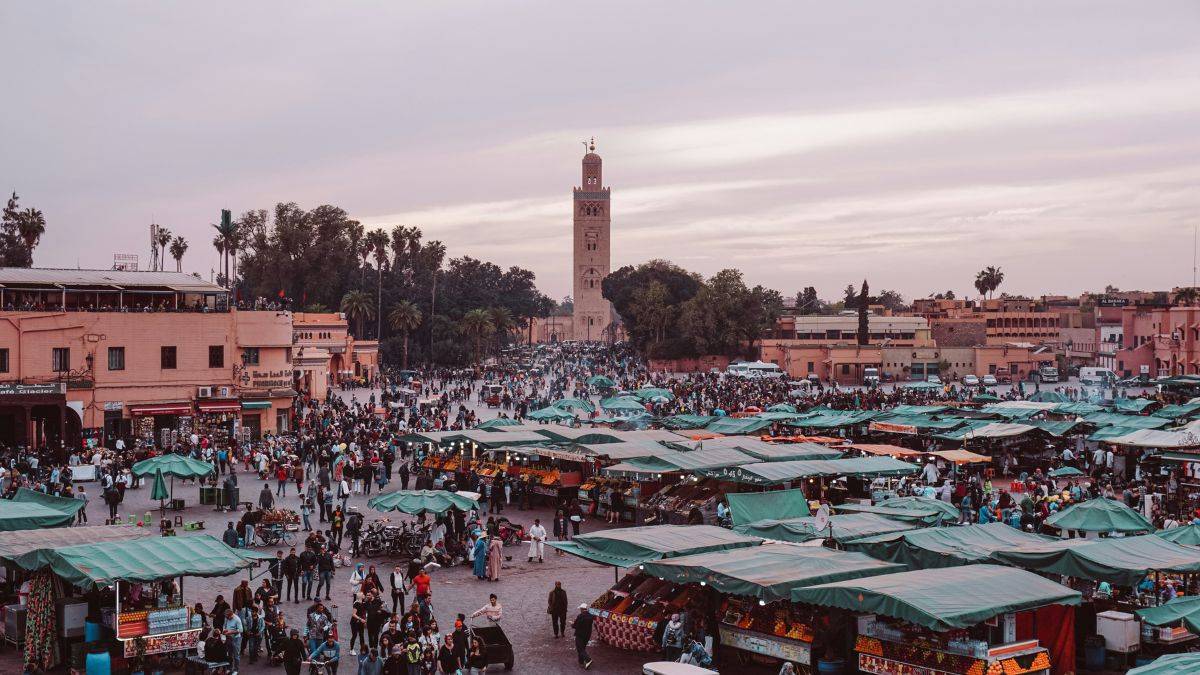 A realistic scene inside a traditional Marrakech artisan workshop where a craftsman shapes copper by hand, warm daylight entering through a small window, tools and handmade pieces around the room, reflecting the living heritage and human craftsmanship of the Red City.