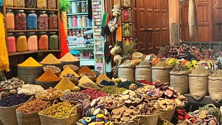 Traditional herbal and spice market in Marrakech displaying colorful piles of medicinal plants, natural ingredients, and handmade remedies.