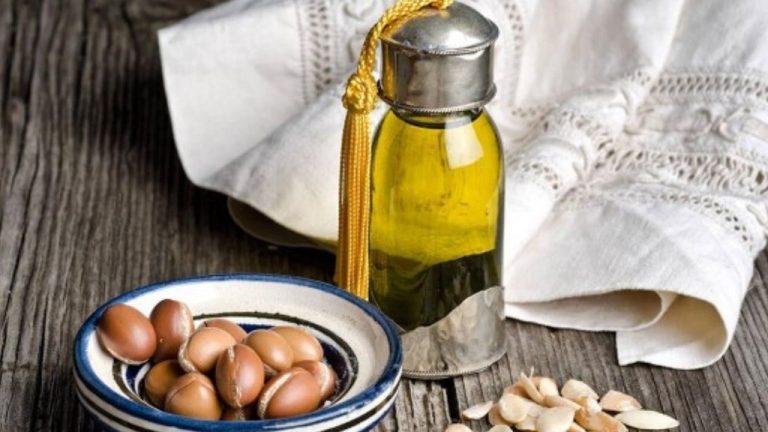 Traditional Moroccan argan oil bottle with argan nuts on a ceramic plate, symbolizing natural wellness, culinary heritage, and sustainable tourism in Morocco.