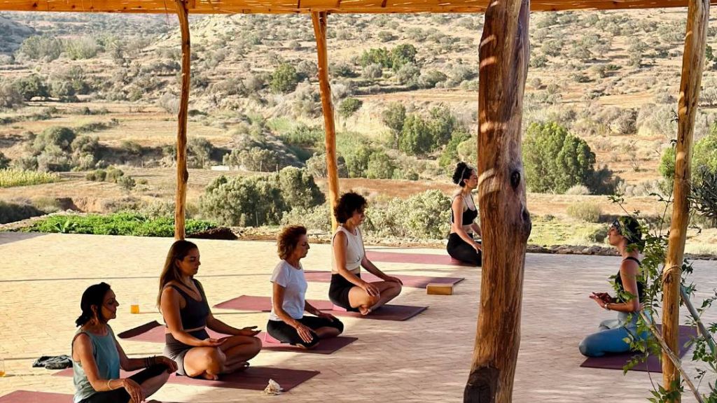 Group meditation session during a yoga retreat in a rooftop of a riad in Essaouira, surrounded by nature and Moroccan landscapes