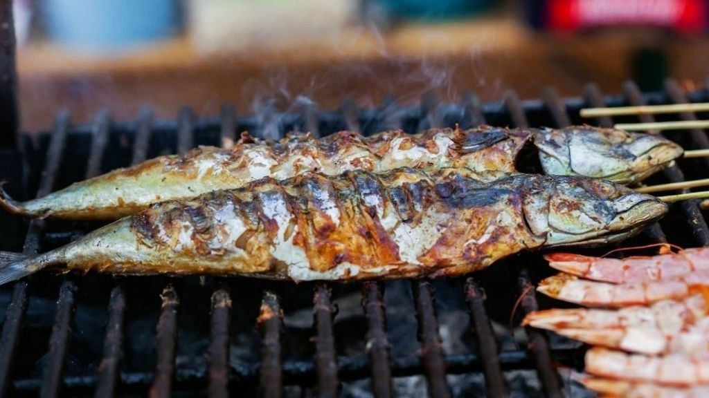Fresh Moroccan sardines grilling over charcoal, showcasing traditional coastal cuisine, street food culture, and healthy Mediterranean seafood.