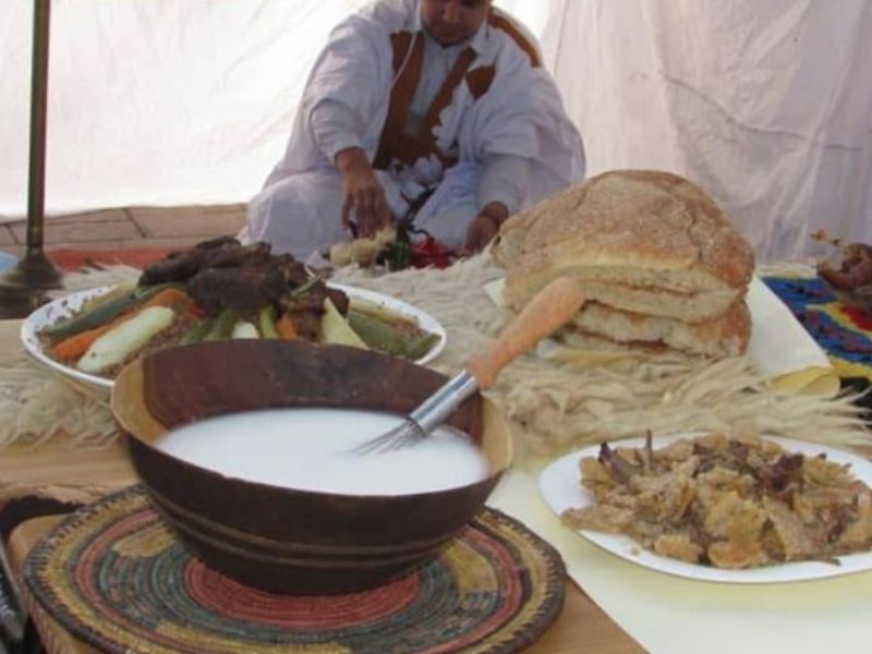 Shared communal dinner at kitesurf camp with people cooking and eating together around simple kitchen